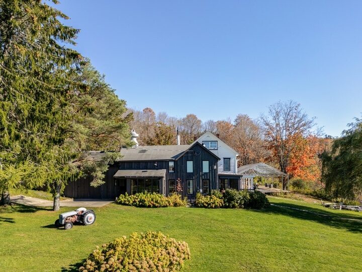 Dark-clad barn exterior at Twelve Ponds with a vintage tractor on the grass.