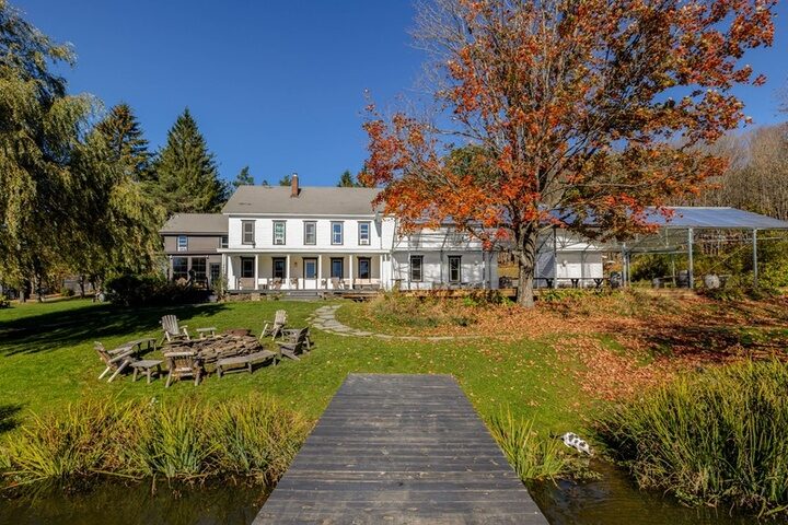 The rear of the farmhouse at Twelve Ponds with fire pit and boardwalk extending over the pond.