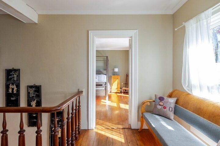 Upstairs landing in the farmhouse at Twelve Ponds with turned banister, wide-plank floors and a window bench.