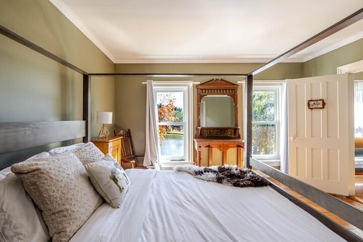 Interior room in the farmhouse at Twelve Ponds with sage walls, antique vanity and a window onto the pond.