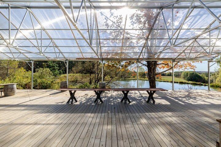 The outdoor covered tented area at Twelve Ponds, harvest table set overlooking the pond.