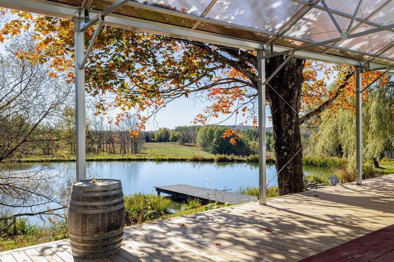 View from under the outdoor tented deck at Twelve Ponds, autumn maple leaves and pond beyond.